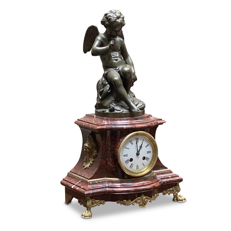 French mantle clock featuring a bronze cupid figure on a rouge marble base