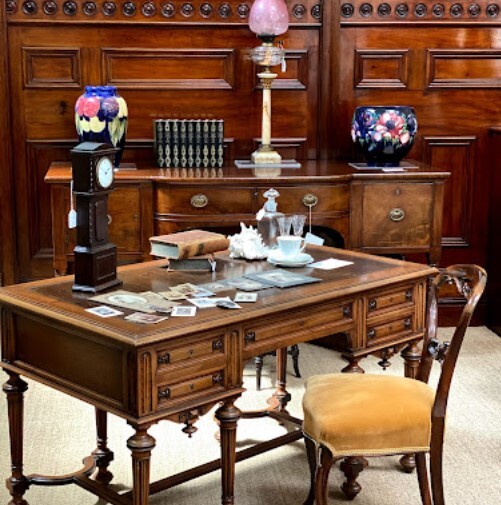 Antique walnut writing desk in opulent library with dark wood panelling