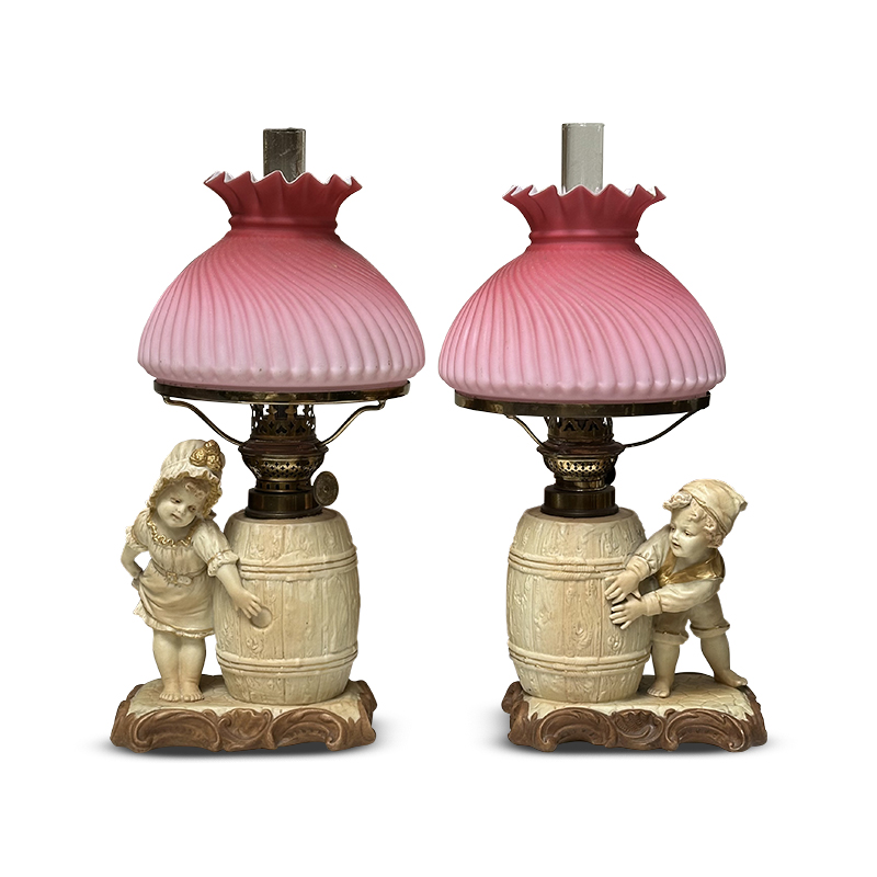Pair Victorian antique decorative oil lamps with pink shades and boy and girl with barrells on base